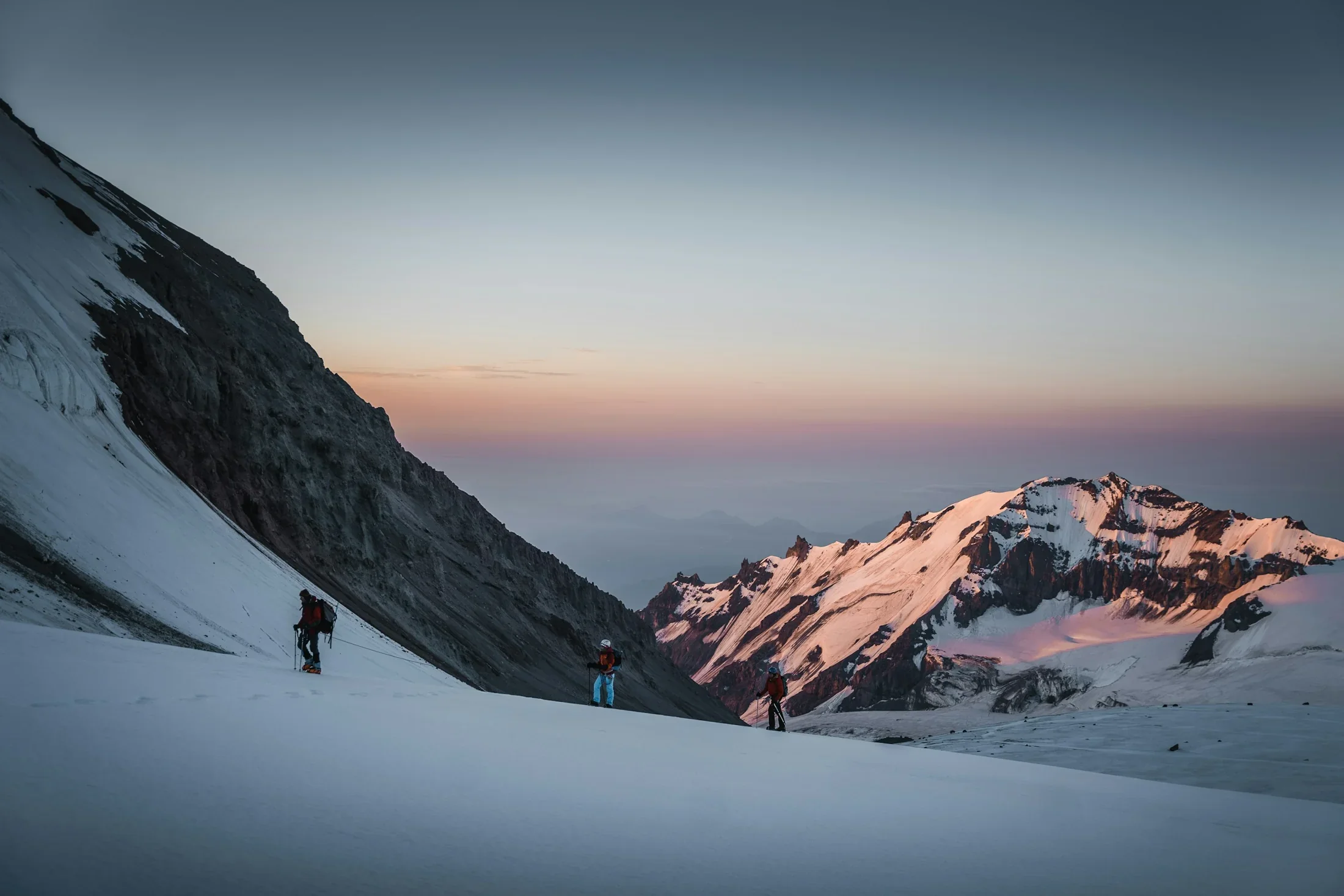 Climbers on a snowy slope of Kazbek in evening light